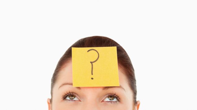Eine Frau mit einem Post-It auf der Stirn, auf dem ein Fragezeichen steht.