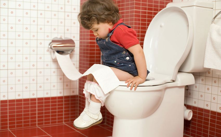 Ein kleines Mädchen sitzt auf dem WC.