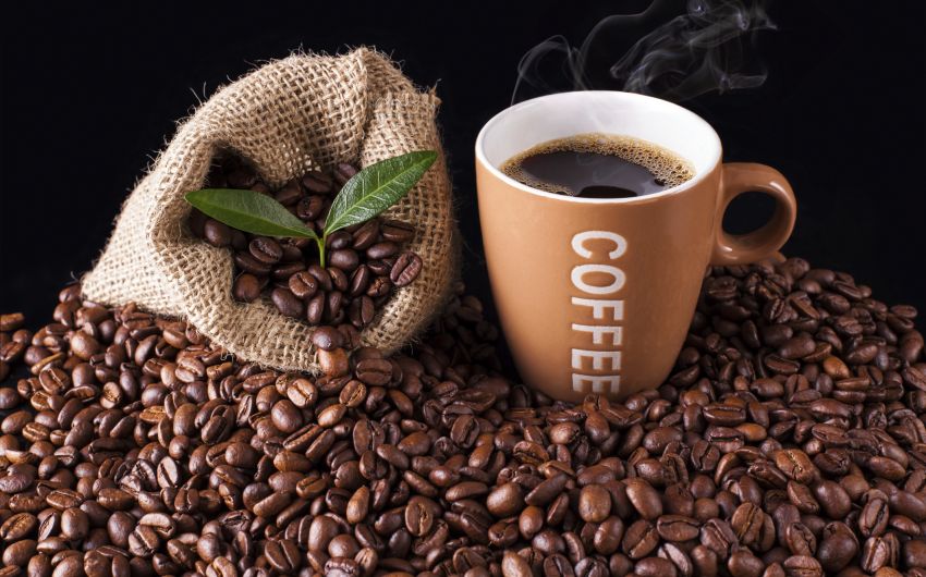 Man sieht Kaffeebohnen und eine Tasse Kaffee.