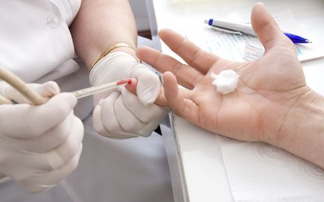 Das Bild zeigt, wie aus einer Fingerspitze Blut entnommen wird.