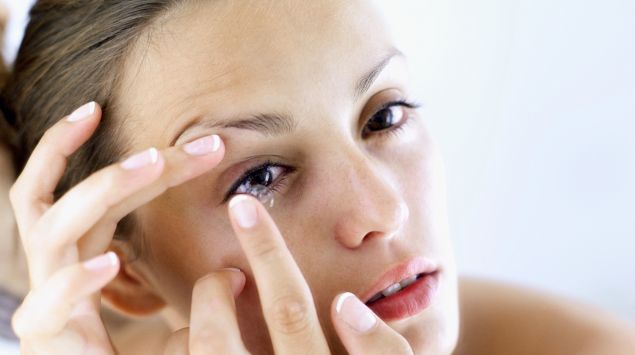 Das Bild zeigt eine Frau, die sich eine Kontaktlinse einsetzt.