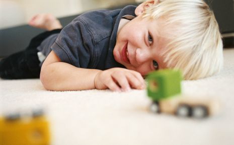 Das Bild zeigt einen kleinen Jungen der mit einem Auto spielt.