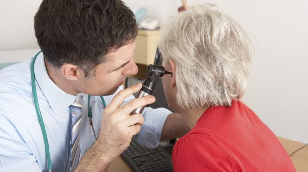 Das Bild zeigt einen Arzt, der einer Patientin ins Ohr schaut.