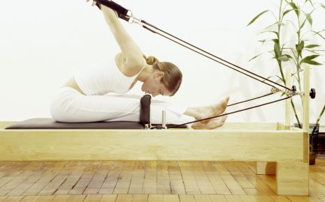 Das Bild zeigt eine Frau auf einem Pilates-Gerät.