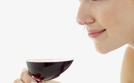 Man sieht eine Frau, die genüsslich ein Glas Rotwein trinkt.