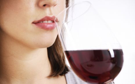 Das Bild zeigt eine Frau, die ein Glas Wein trinkt.
