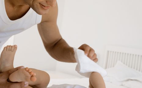 Ein Vater wickelt einen Säugling.