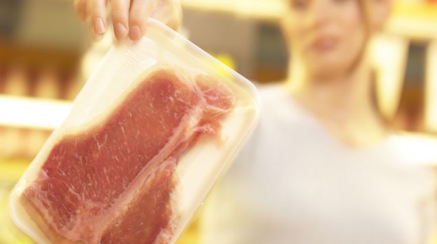 Man sieht eine Frau, die einen Beutel mit rohem Fleisch in den Händen hält.