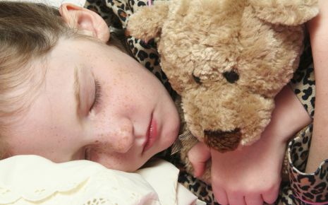Man sieht ein schlafendes Mädchen mit Teddybär.