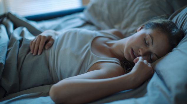 Eine junge Frau liegt in einem Bett und schläft.