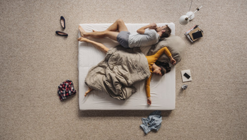 Ein Mann und eine Frau liegen auf einer Matratze.