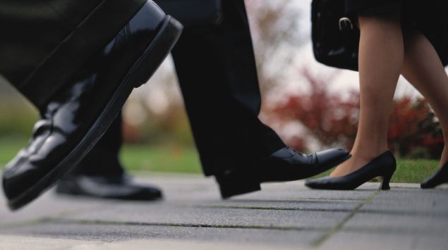 Man sieht die Schuhe von Menschen, die auf der Straße gehen.