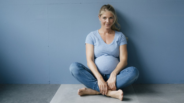 Eine Schwangere sitzt auf dem Fußboden: Hämorrhoiden in der Schwangerschaft werden meist mit Salben, Cremes und anderen konservativen Maßnahmen behandelt.