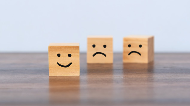 Holzwürfel mit traurigen und fröhlichen Smileys: Bei der Zyklothymia schwankt die Stimmung zwischen Hypomanie und Depression.