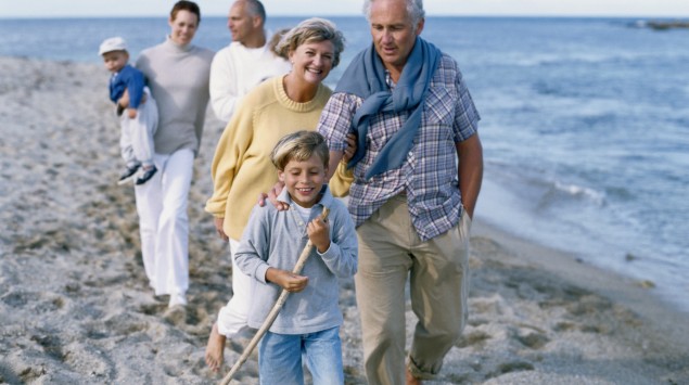 Eine Familie spaziert den Strand entlang.