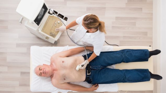 Eine Ärztin führt bei einem älteren Mann einen Ultraschall des Bauchbereichs durch.