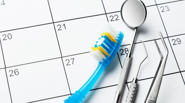 Zahnarzttermin: Man sieht eine Zahnbürste, einen Dentalsspiegel und andere Zahnarzt-Geräte auf einem Kalenderblatt.